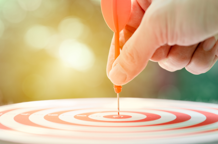 Business target concept of how to identify your target audience, male hand holding arrow dart at center targeting hit highest point.